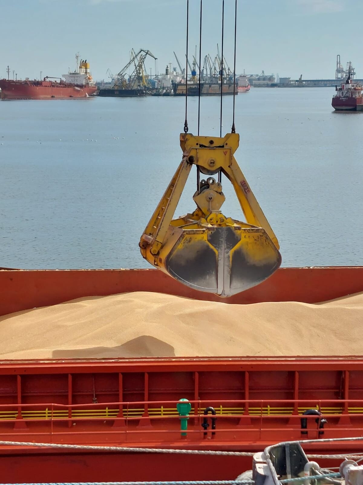 Grab crane loading grain into the cargo hold of a bulk carrier
