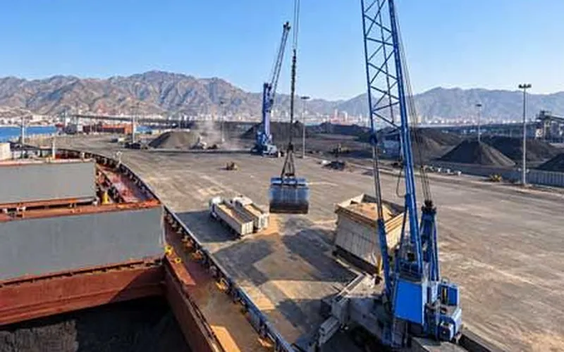 Mobile harbour cranes loading a bulk carrier at a mineral terminal — CEO Insights Asia article on mining export logistics