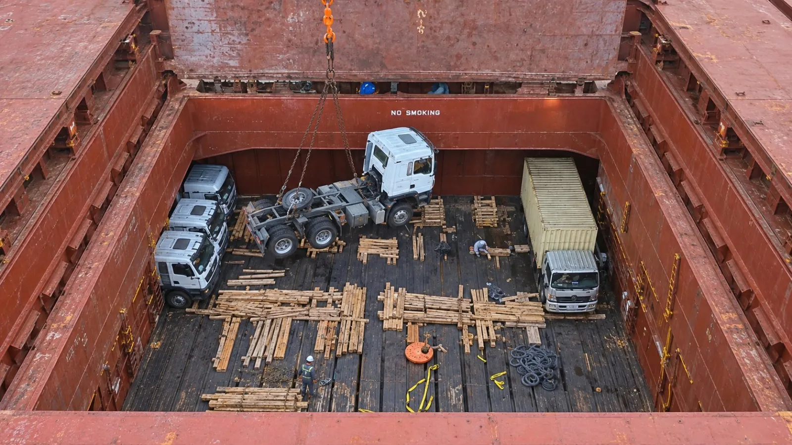 Trucks and machinery stowed on timber dunnage in the hold of a general cargo vessel
